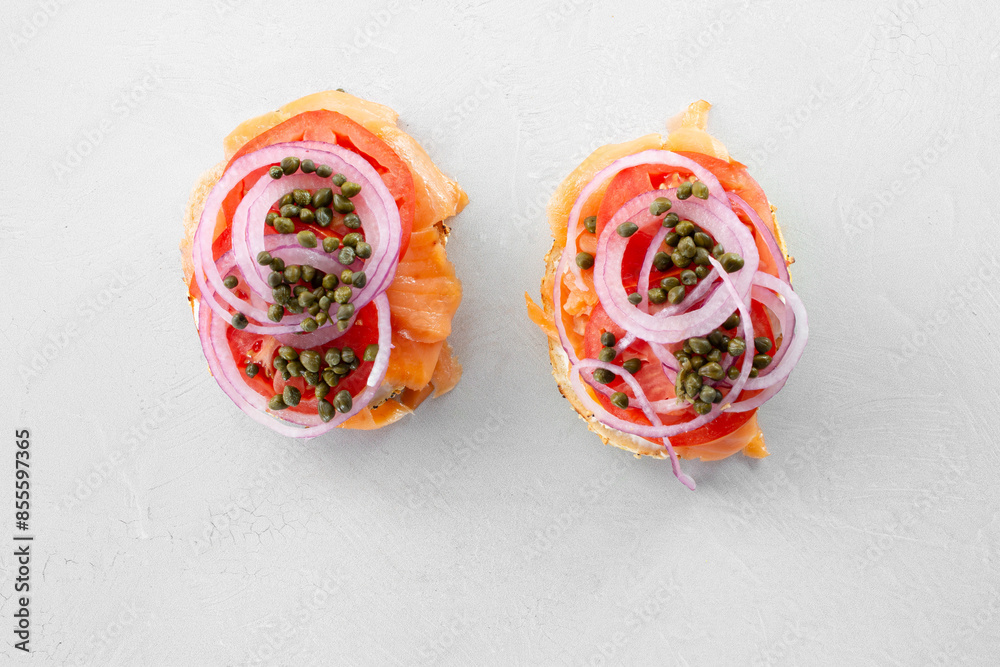 A top down view of salmon bagels, against a white background. A top down view of salmon bagels, against a white background.