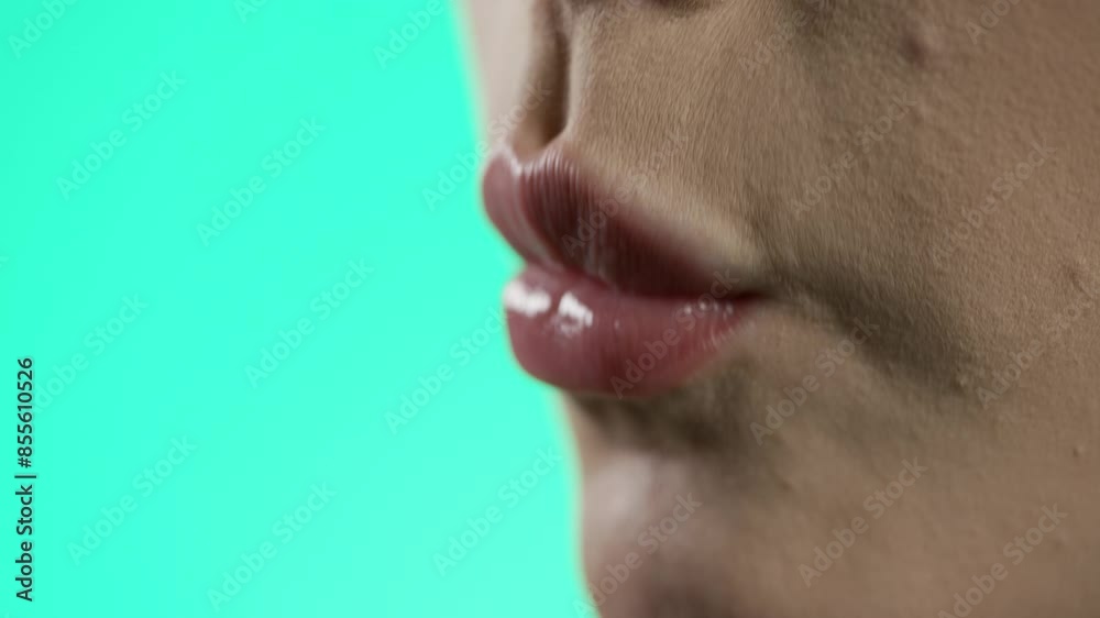 woman eating strawberry in neon lighting, close-up of face and mouth, green background