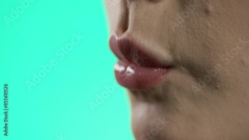 woman eating strawberry in neon lighting, close-up of face and mouth, green background photo