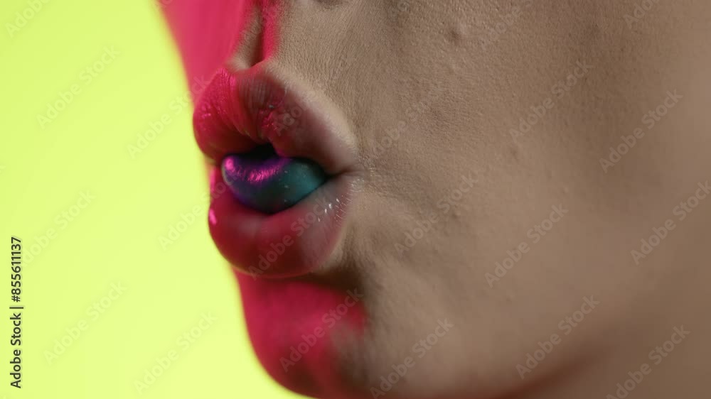 mouth close-up of woman chewing bubblegum and blowing bubble, close-up shot on yellow background