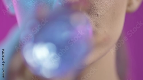 woman taking a sip of water from waterbottle in close-up, girly nail polish and red lipstick lips on purple background photo