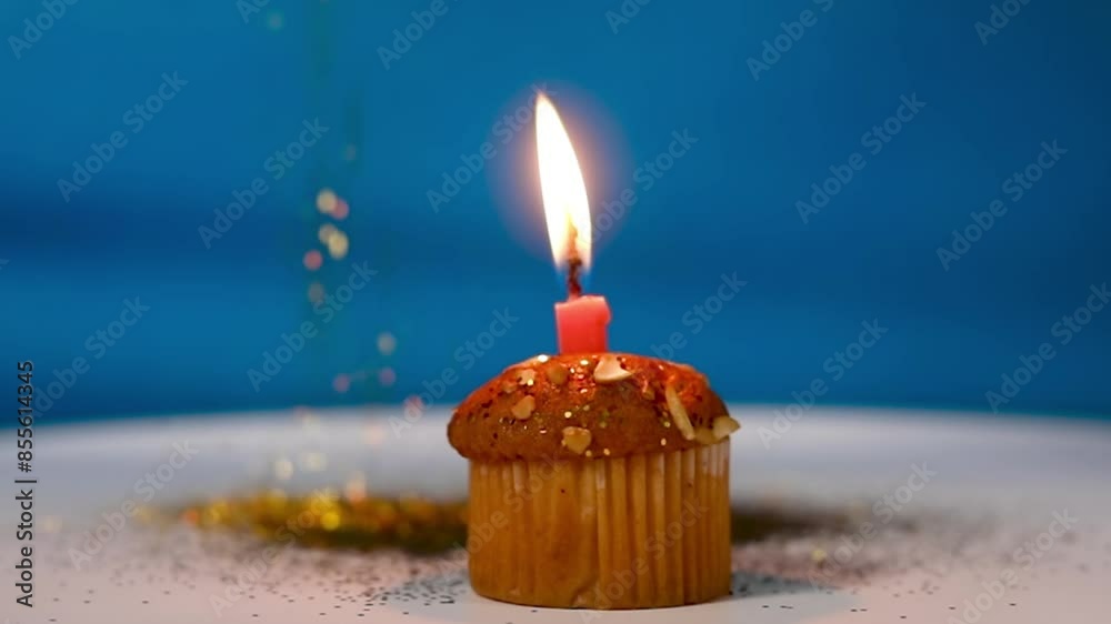 Birthday celebration: brightly lit festive candles on top of cupcake muffins with golden confetti falling. Birthday celebration: brightly lit festive candles on top of cupcake muffins with golden confetti falling.