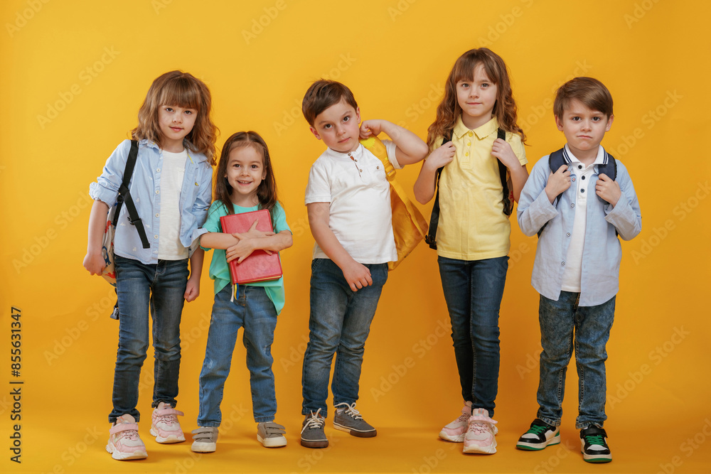 Obraz premium Standing and posing. Kids are together against yellow background