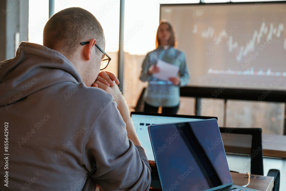 Female business trainer is against projector with business data, teaching the man Female business trainer is against projector with business data, teaching the man