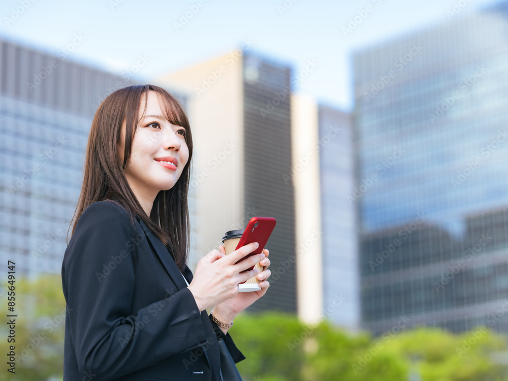 Fototapeta premium 街でスマホを使う女性ビジネスパーソン