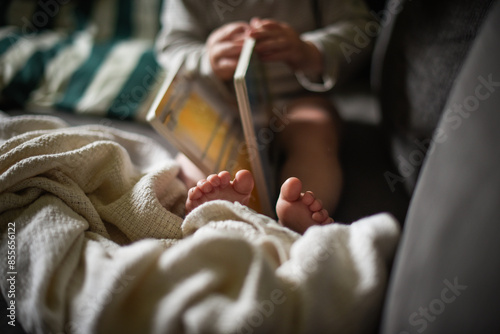 Child reading a board book with feet wrapped in a cozy blanket