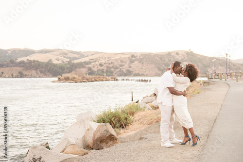 Couple giving each other a kiss in front of a scenic background photo