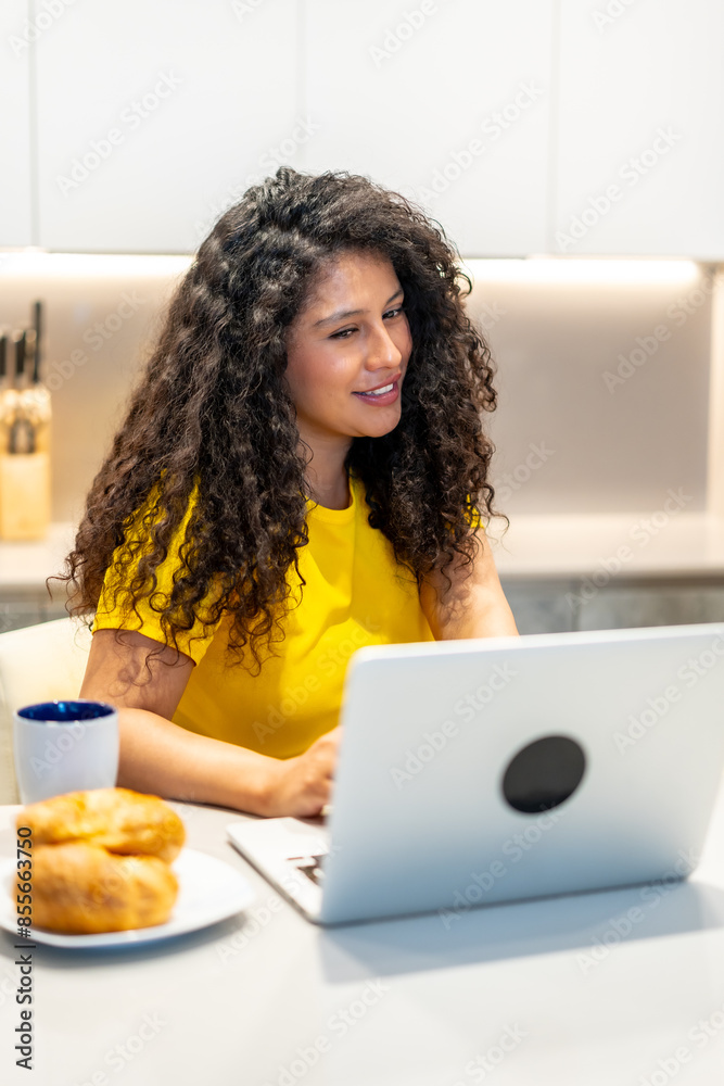 Woman eating breakfast and attending a video call at home