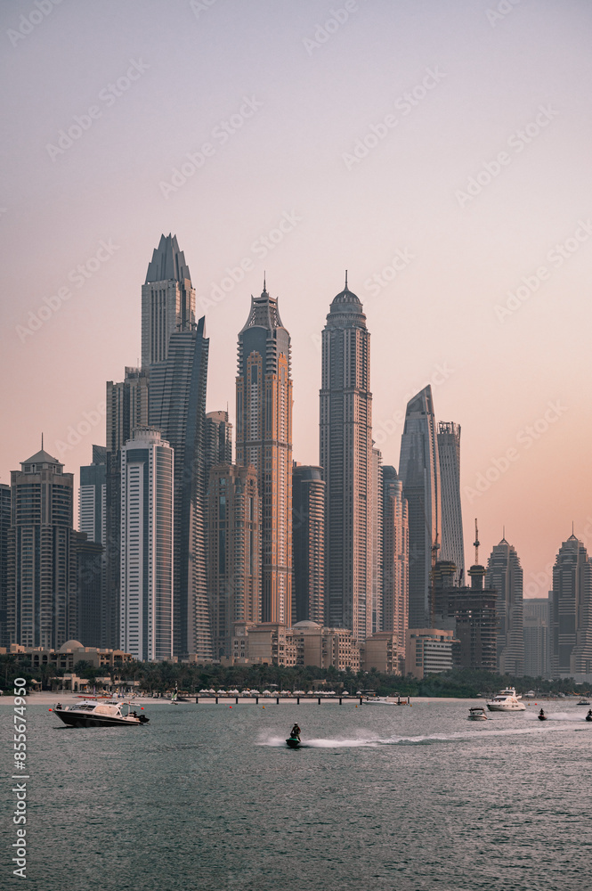 Fototapeta premium Dubai city skyline at sunset from the sea and jet skis