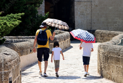 Father protects his children with umbrellas from the sun on a very hot day. Heat record with temperatures above 40° celsius in summer