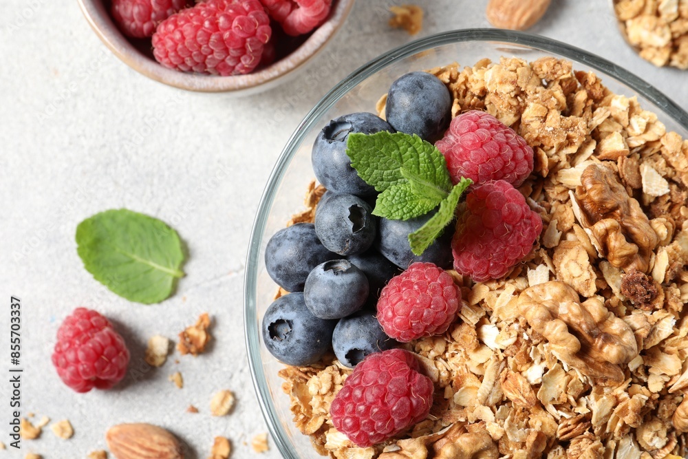 Tasty granola with berries, nuts and mint on grey table, flat lay Tasty granola with berries, nuts and mint on grey table, flat lay