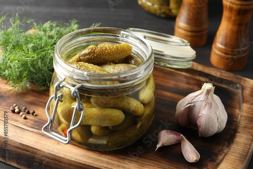 Pickled cucumbers in jar, garlic and dill on grey wooden table