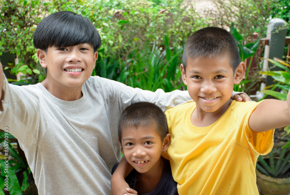 Group of Asian young boys friends taking selfie picture smiling charming and looking at the camera phone against outdoor green forest background for concept of multicultural people having fun day.