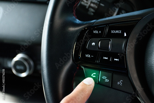 Fingers pressing the answer call button on the car steering wheel with green light of a modern car luxury in 2024.