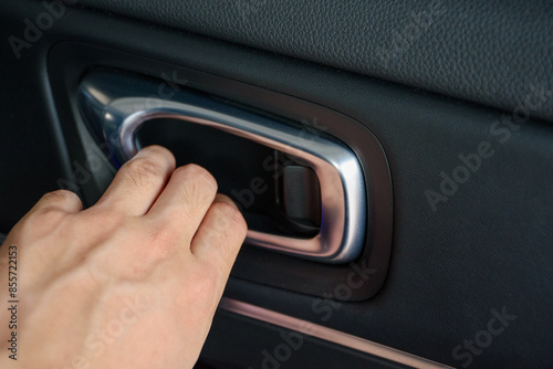 Close up man hand opening a car vehicle door lever or inner door handle is the interior of a modern and luxurious car.