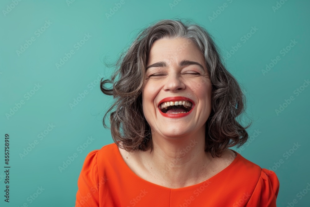 Portrait of a glad woman in her 40s laughing in solid color backdrop Portrait of a glad woman in her 40s laughing in solid color backdrop