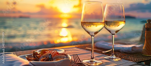 Fototapeta Naklejka Na Ścianę i Meble -  Romantic dinner at the beach restaurant overlooking the sunset on the ocean, on a beautifully served table seafood and white wine. Copy space image. Place for adding text or design