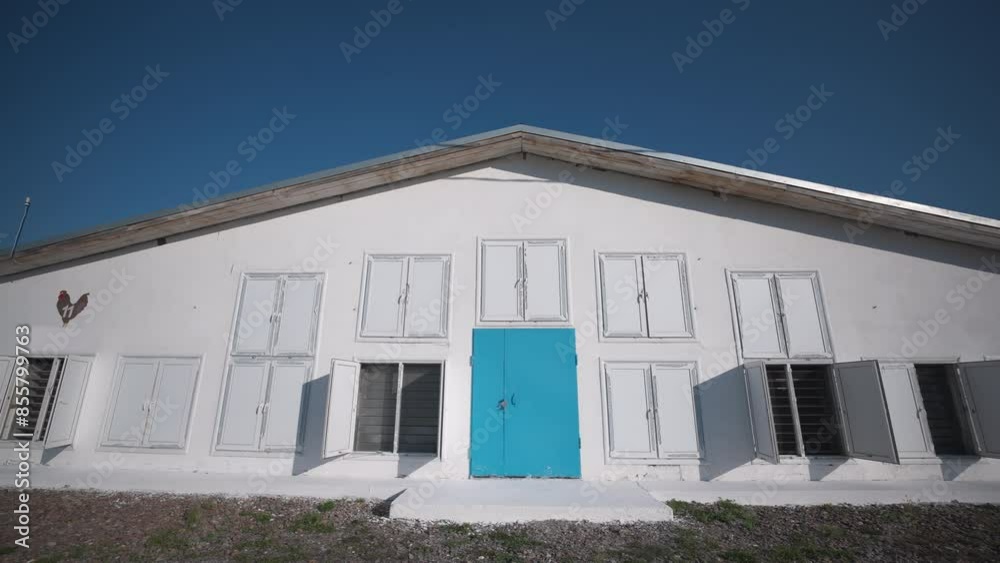 Huge white building with blue doors used for agricultural poultry farming. Raising lots of domesticated birds at the poultry farm building. Poultry farm building with many windows. Huge white building with blue doors used for agricultural poultry farming. Raising lots of domesticated birds at the poultry farm building. Poultry farm building with many windows.