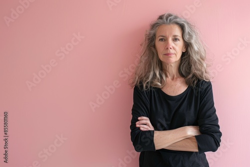 Portrait of a tender woman in her 50s with arms crossed on solid pastel color wall