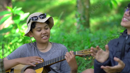 Group of young people singing together in forest, enjoying nature and togetherness. Concept of youth vacation, camping activity, friendship, relaxed lifestyle, outdoor fun in 4K video.
