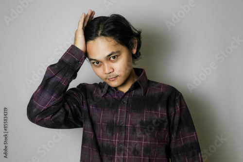 Portrait of an Asian Indonesian young man wearing a purple shirt with a random expression when photographed with an isolated white background photo