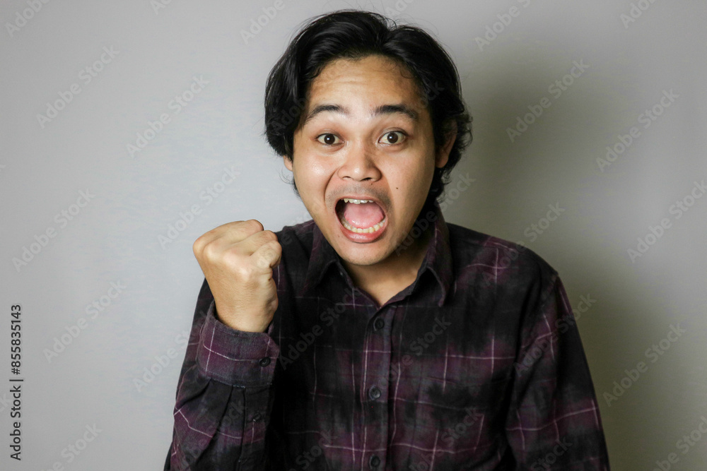 Portrait of an Asian Indonesian young man wearing a purple shirt with a random expression when photographed with an isolated white background Portrait of an Asian Indonesian young man wearing a purple shirt with a random expression when photographed with an isolated white background