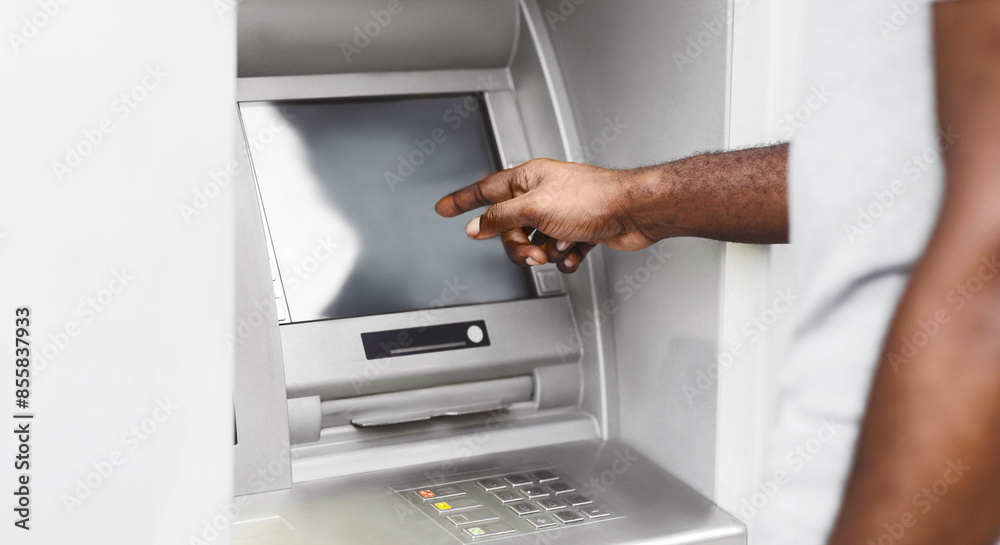 A close-up of a persons hand interacting with an ATM screen. The persons arm and shoulder are visible in the background. A close-up of a persons hand interacting with an ATM screen. The persons arm and shoulder are visible in the background.