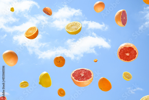 Citrus fruit flying on a blue sky with clouds. Summer aesthetic visual colorful concept.