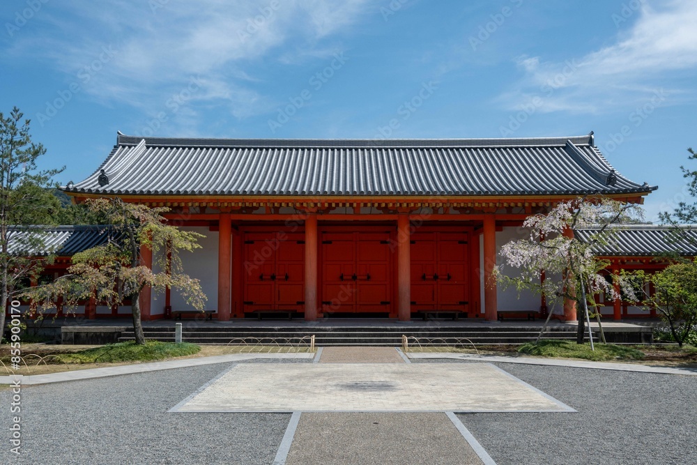 The traditional Japanese Sanjusangendo temple with red pillars and doors under a clear blue sky. The traditional Japanese Sanjusangendo temple with red pillars and doors under a clear blue sky.