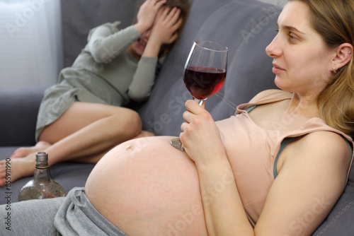 A pregnant woman drinks alcohol at home, a small child is crying in the background. problems of alcoholism and the period of bearing a child.danger of losing a baby, miscarriage. alcoholic