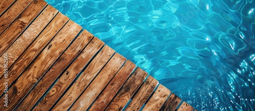 Diagonal lines of wood in detail decking and blue water swimming pool abstract background. Copy space image. Place for adding text and design photo