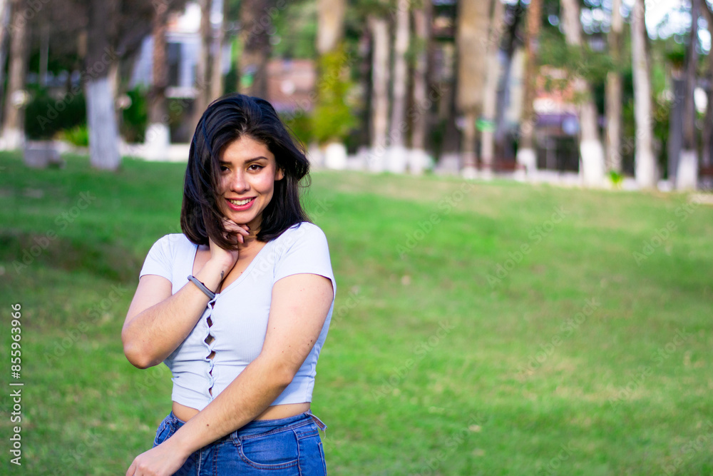 20s young hispanic woman smiling in blue blouse posing in green park. 20s young hispanic woman smiling in blue blouse posing in green park.