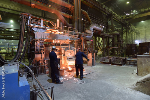Φωτογραφία Workers in protective equipment in a foundry during the production of steel comp