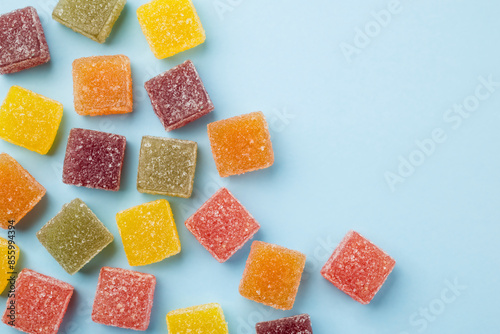 Assorted jelly candies on blue background, top view.