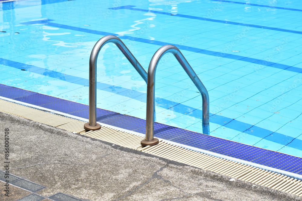 Obraz premium Closeup of Stainless Steel Handrail or Grab bars ladder in the clear blue swimming pool, Concept for convenience in entering the swimming pool at Thailand.