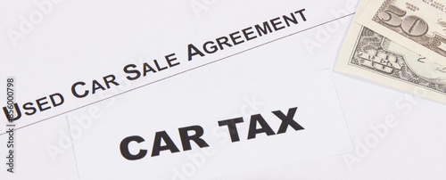 Inscription car tax, dollar banknotes and vehicle sales agreement. Sales, purchases, taxation of automobile