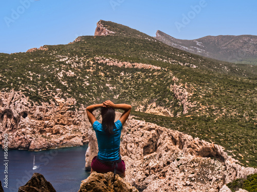 Una Donna sportiva si gode la vista di Capo Caccia dalla Grotta dei vasi rotti di Alghero, Sardinia.