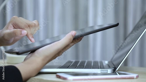 Businessman interacting with tablet with open laptop There was a smartphone on a nearby table. Efficient work and technology savvy Using AI technology, artificial intelligence or AI technology
