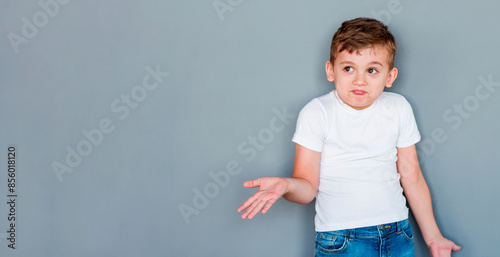 Little cute boy kid wearing casual white t-shirt clueless and confused expression with arms and hands raised. doubt concept.