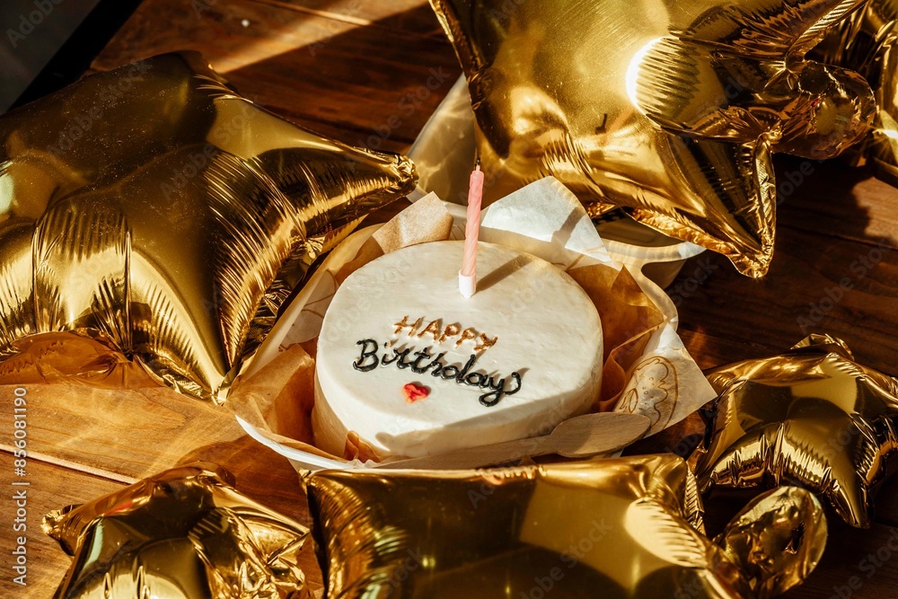 Valokuva gold balloons and a beautifully simple birthday cake to mark the passage into ad