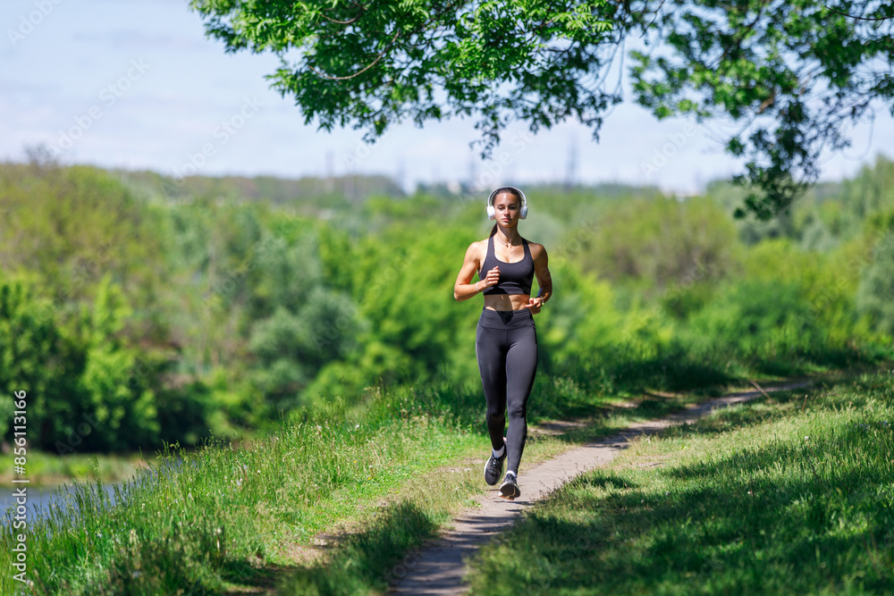 Young fitness woman jogging in park near the river at sunny morning Young fitness woman jogging in park near the river at sunny morning