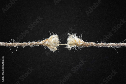 Frayed Rope About to Break Against Textured Black Paper Background with Copy Space