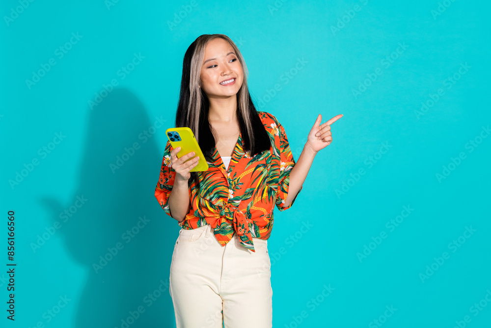 Photo of cheerful pretty lady dressed orange shirt reading modern gadget pointing empty space isolated blue color background Photo of cheerful pretty lady dressed orange shirt reading modern gadget pointing empty space isolated blue color background