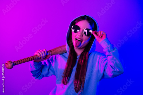 Photo of cheerful funny little lady dressed hoodie rising bat stick out empty space isolated neon purple color background