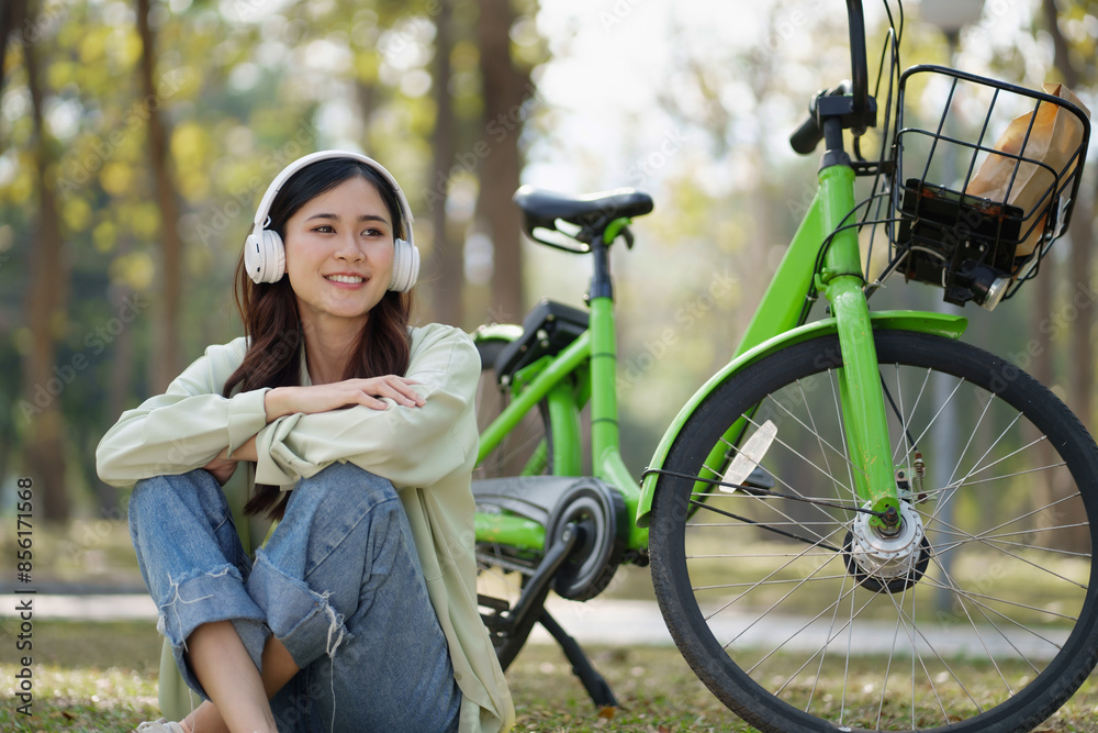 Fototapeta premium Asian Woman sitting at outdoor park wearing headphone listen music