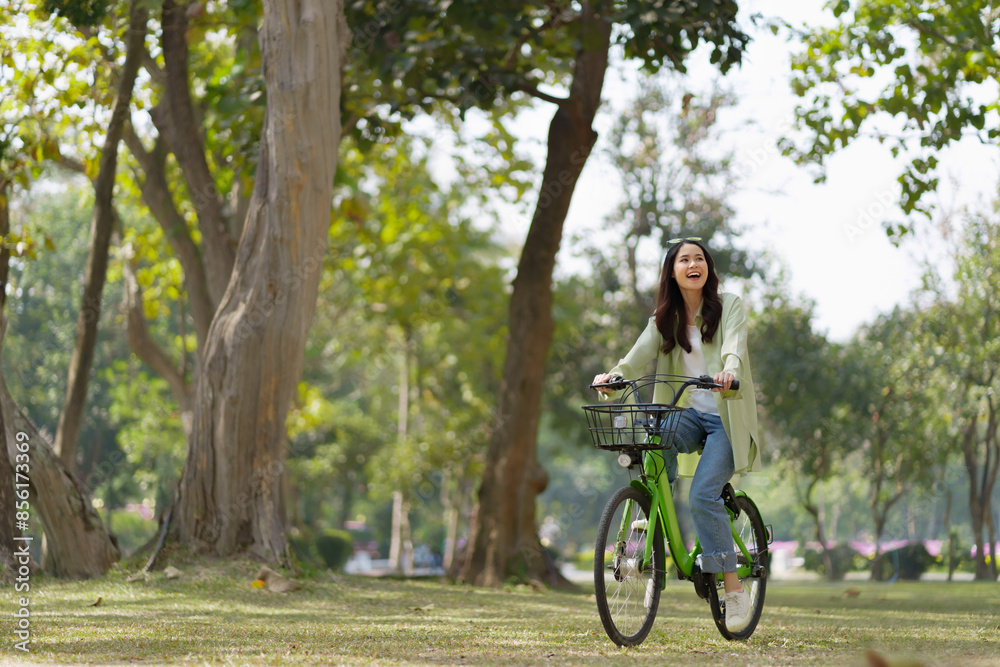 Happy asian woman riding bicycle on public park. Happy asian woman riding bicycle on public park.