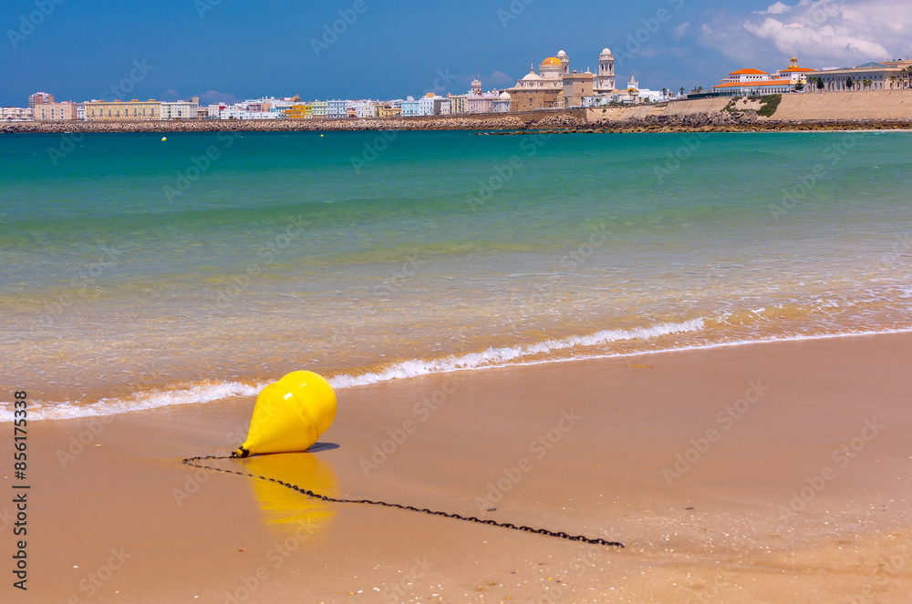 Yellow buoy on Cadiz beach with cityscape and blue sea in the background, Spain Yellow buoy on Cadiz beach with cityscape and blue sea in the background, Spain