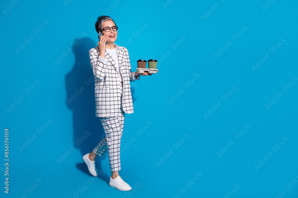 Fototapeta premium Photo of cheerful successful woman wear white stylish clothes walk carry coffee empty space isolated on blue color background