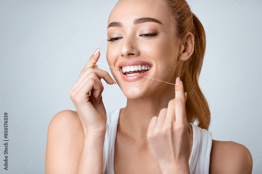 Oral Hygiene. Smiling Woman Using Dental Floss Over Grey Background Oral Hygiene. Smiling Woman Using Dental Floss Over Grey Background