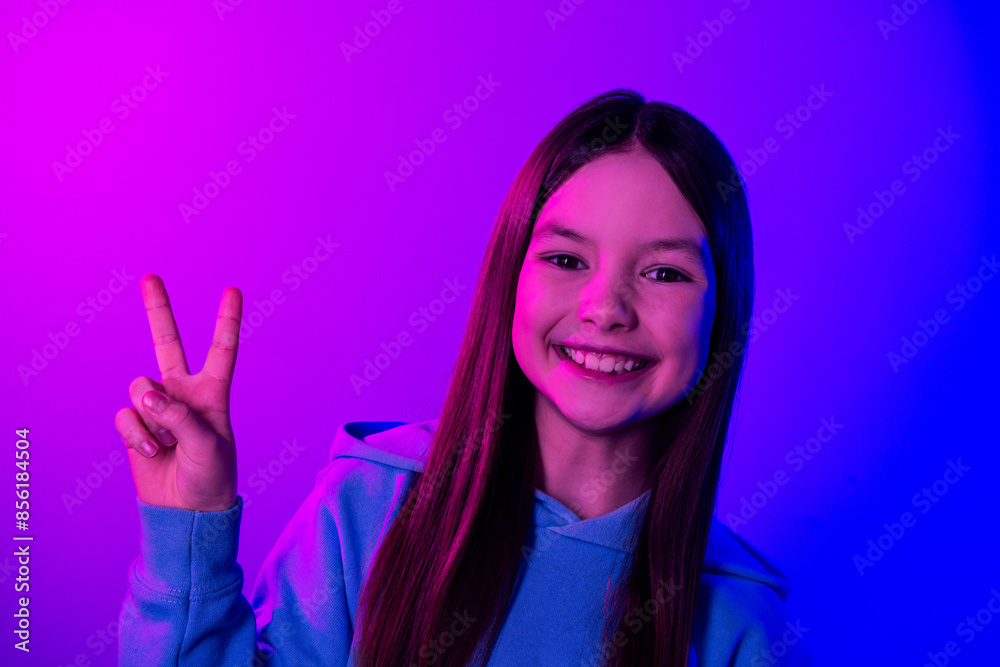 Photo of shiny attractive little lady dressed hoodie showing v-sign empty space isolated neon pink color background Photo of shiny attractive little lady dressed hoodie showing v-sign empty space isolated neon pink color background